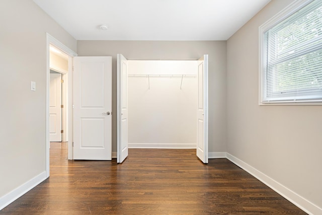 unfurnished bedroom with dark wood-style floors, baseboards, and a closet