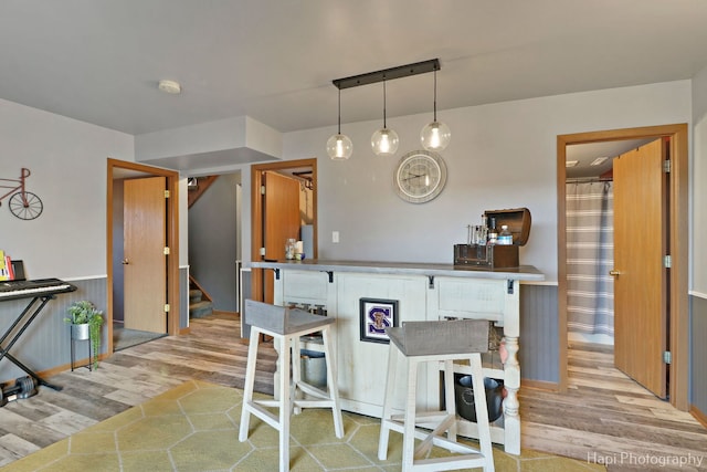 kitchen featuring light wood finished floors, brown cabinetry, and decorative light fixtures