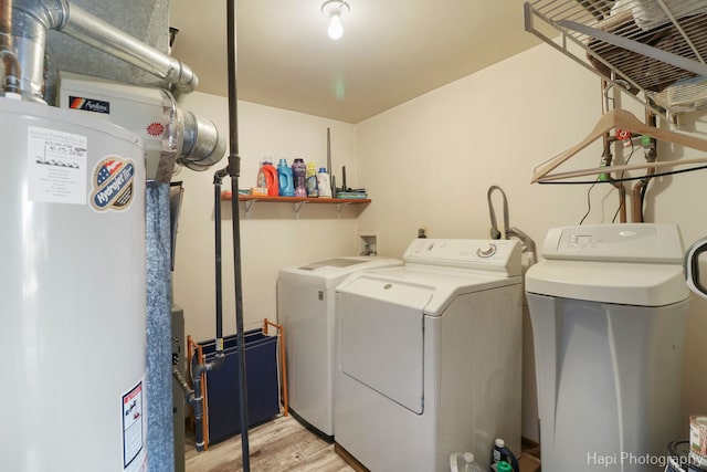 clothes washing area with light wood-style flooring, laundry area, water heater, and washer and clothes dryer