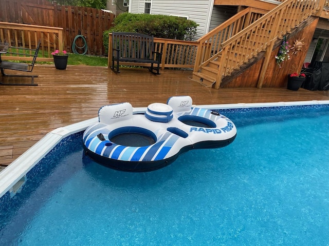 pool with stairway, fence, and a wooden deck