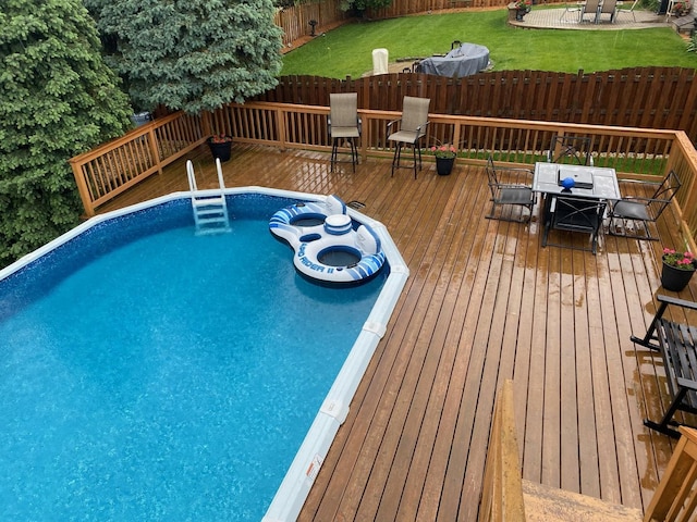 pool with outdoor dining space, a fenced backyard, and a wooden deck