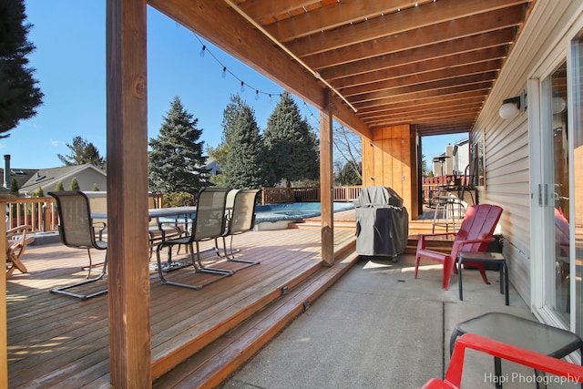 wooden deck featuring outdoor dining area, a grill, and a fenced in pool