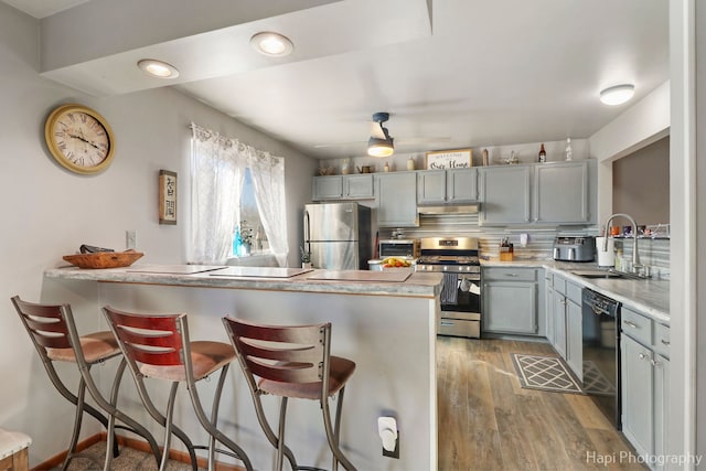 kitchen with stainless steel appliances, light countertops, a peninsula, and gray cabinetry