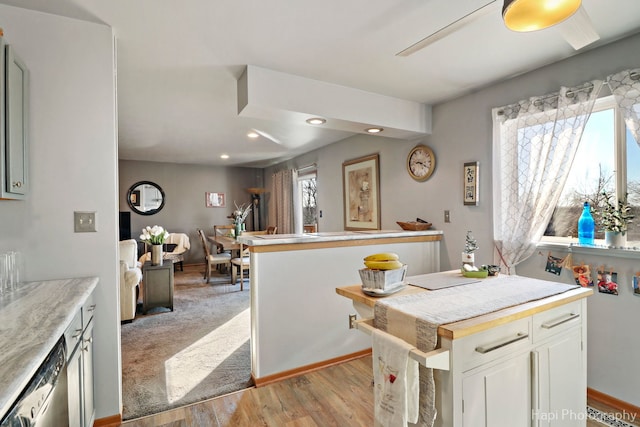 kitchen featuring light wood finished floors, light countertops, open floor plan, white cabinetry, and dishwasher