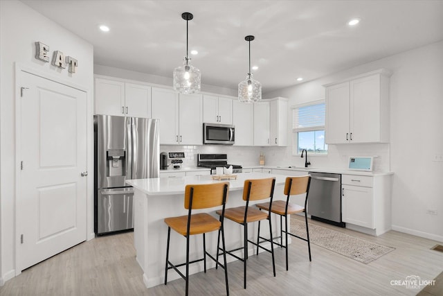 kitchen featuring stainless steel appliances, light countertops, white cabinetry, a kitchen island, and a sink