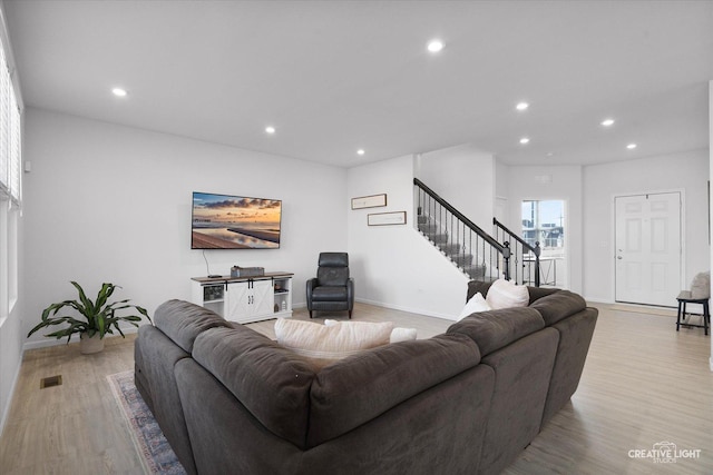 living area with recessed lighting, visible vents, baseboards, stairs, and light wood finished floors