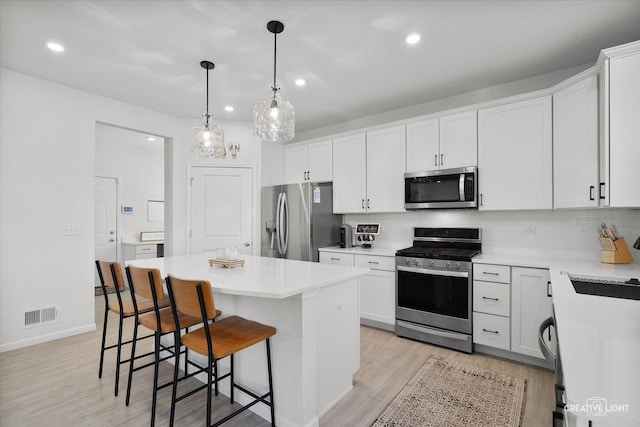 kitchen featuring appliances with stainless steel finishes, a center island, light countertops, and white cabinets