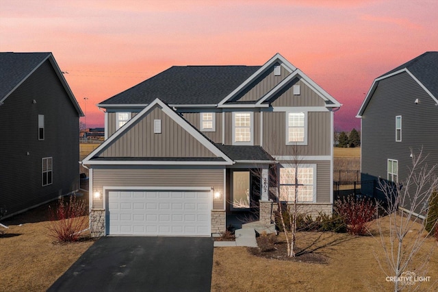 craftsman-style house featuring a garage, stone siding, aphalt driveway, board and batten siding, and a front yard