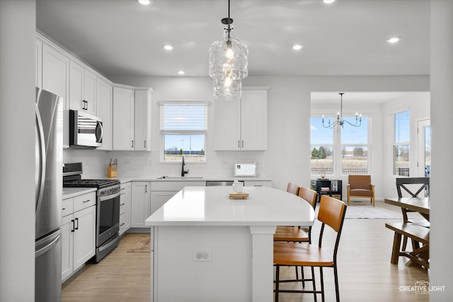 kitchen with appliances with stainless steel finishes, a center island, white cabinets, and light countertops