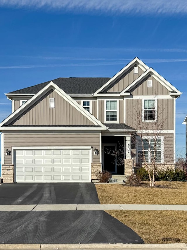 craftsman-style house with driveway, stone siding, board and batten siding, and roof with shingles