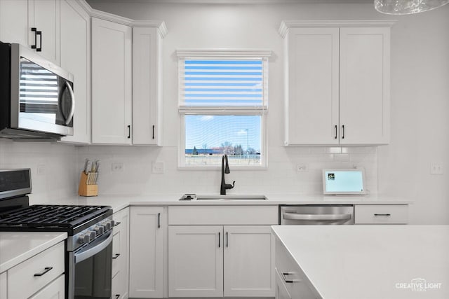 kitchen with decorative backsplash, appliances with stainless steel finishes, light countertops, white cabinetry, and a sink