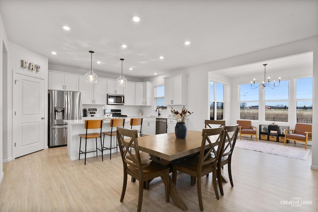 dining area featuring light wood-type flooring, an inviting chandelier, and recessed lighting