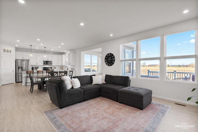 living room with baseboards, visible vents, light wood-style flooring, and recessed lighting