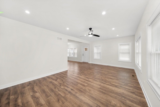 unfurnished living room with dark hardwood / wood-style flooring and ceiling fan