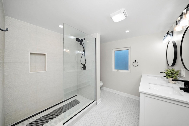 bathroom featuring tile patterned flooring, vanity, a tile shower, and toilet