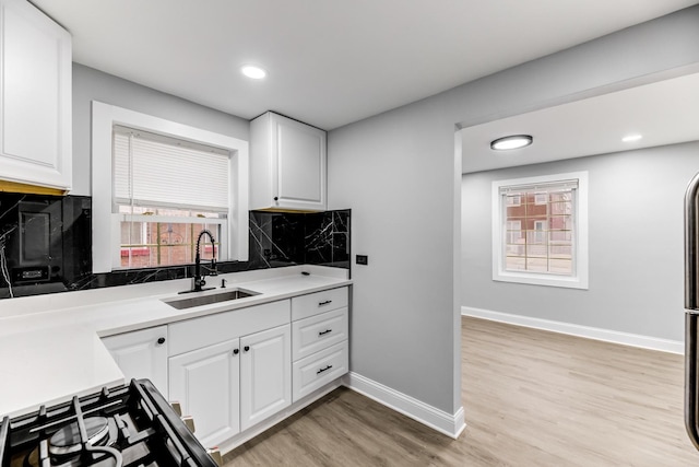 kitchen with white cabinetry, sink, decorative backsplash, and light wood-type flooring