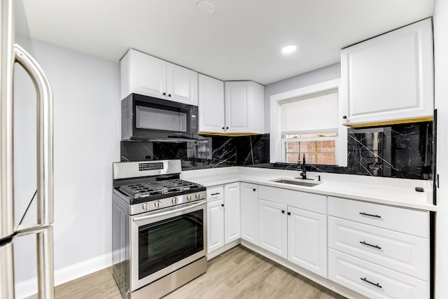 kitchen with sink, stainless steel range with gas cooktop, white cabinets, and refrigerator