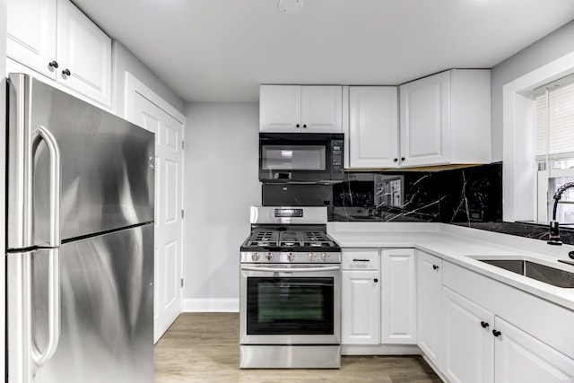 kitchen with sink, light hardwood / wood-style flooring, appliances with stainless steel finishes, white cabinetry, and decorative backsplash