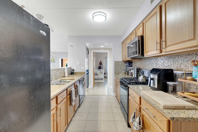 kitchen with light tile patterned floors, a textured ceiling, a sink, backsplash, and black appliances