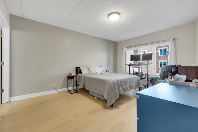 bedroom with light wood-type flooring, a textured ceiling, and baseboards