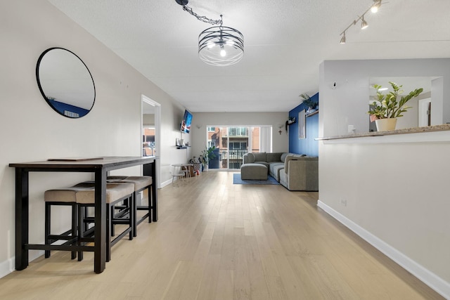 interior space featuring baseboards, a textured ceiling, and light wood-style floors