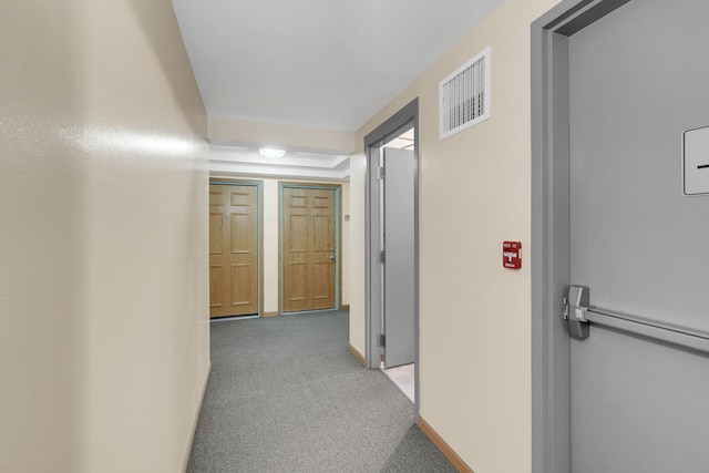 hallway featuring carpet, visible vents, and baseboards