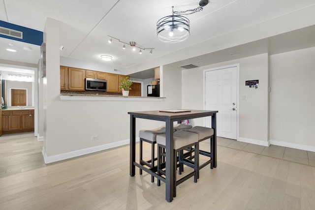 dining space with light wood-style floors, baseboards, visible vents, and a textured ceiling