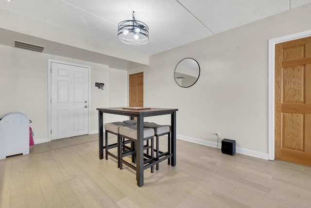 dining space featuring light wood-style flooring, visible vents, and baseboards