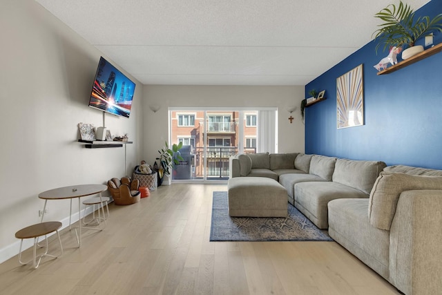 living room with a textured ceiling, baseboards, and wood finished floors