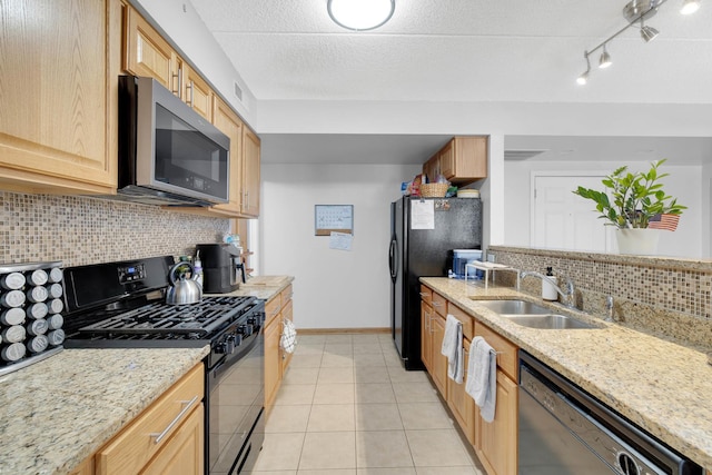 kitchen with light tile patterned floors, baseboards, light stone countertops, black appliances, and a sink