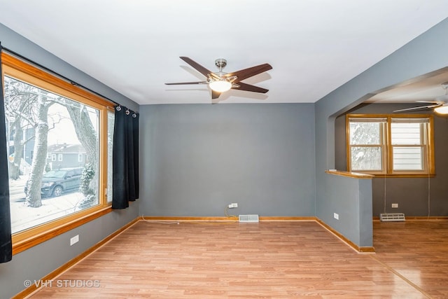 empty room with light hardwood / wood-style flooring, a wealth of natural light, and ceiling fan