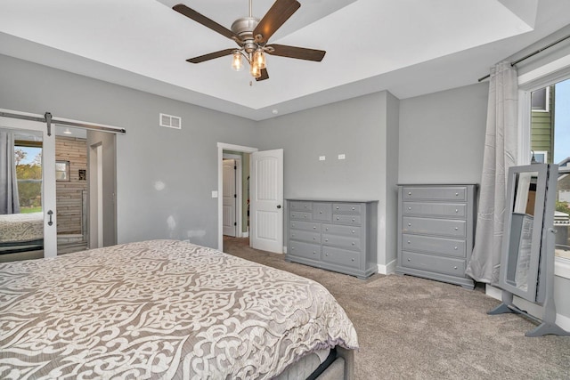 carpeted bedroom featuring ceiling fan and a barn door