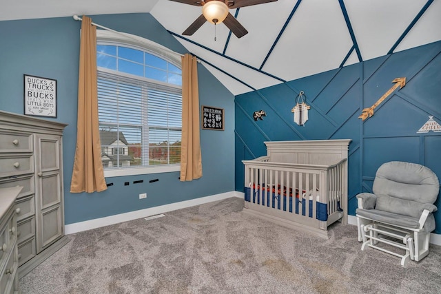 carpeted bedroom with ceiling fan, vaulted ceiling, and a nursery area