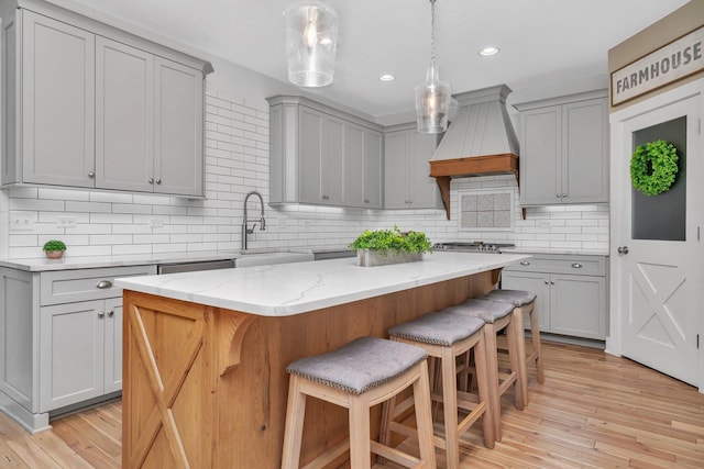 kitchen with a center island, custom range hood, and gray cabinetry