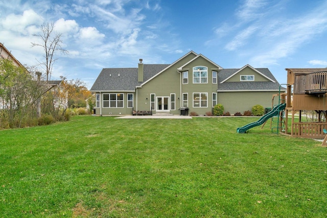 back of property with a yard, a patio, and a playground