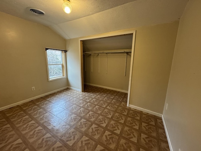 unfurnished bedroom featuring lofted ceiling, a textured ceiling, and a closet