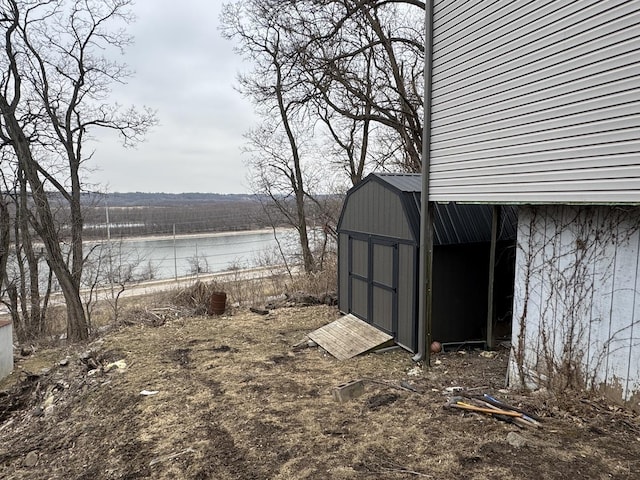 view of yard featuring a water view and a shed