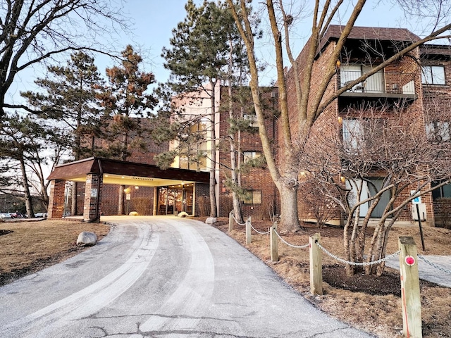 exterior space with a carport, brick siding, and driveway