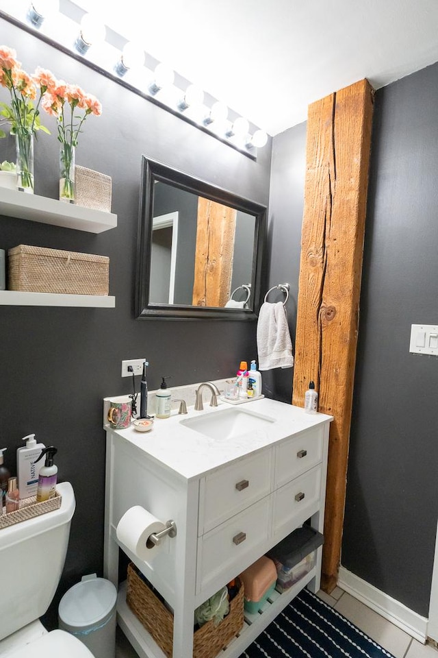 half bathroom featuring tile patterned flooring, baseboards, vanity, and toilet