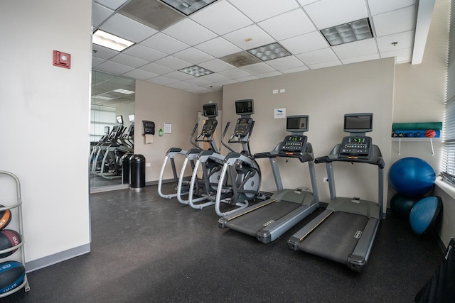 exercise room with a drop ceiling and baseboards