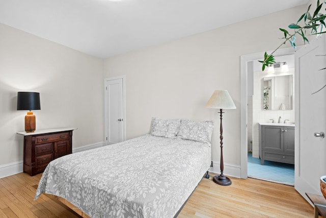 bedroom with connected bathroom, sink, and light hardwood / wood-style floors