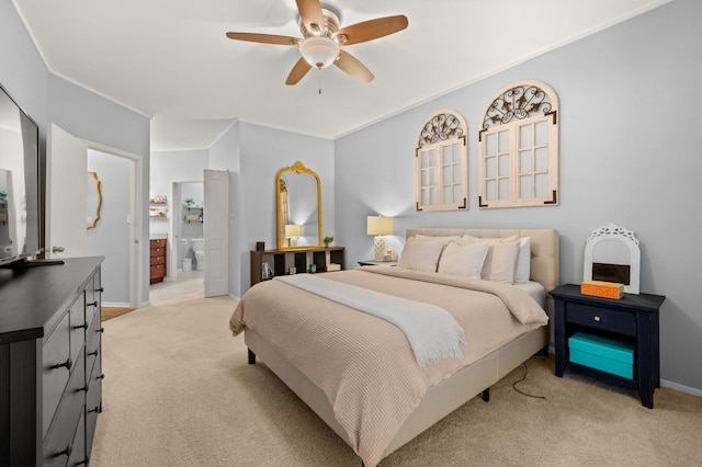 bedroom featuring light carpet, ceiling fan, and ensuite bath