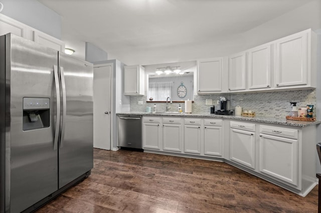 kitchen with tasteful backsplash, white cabinetry, sink, stainless steel appliances, and dark wood-type flooring