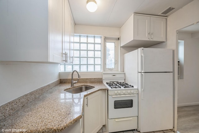 kitchen with white appliances, light stone countertops, sink, and white cabinets