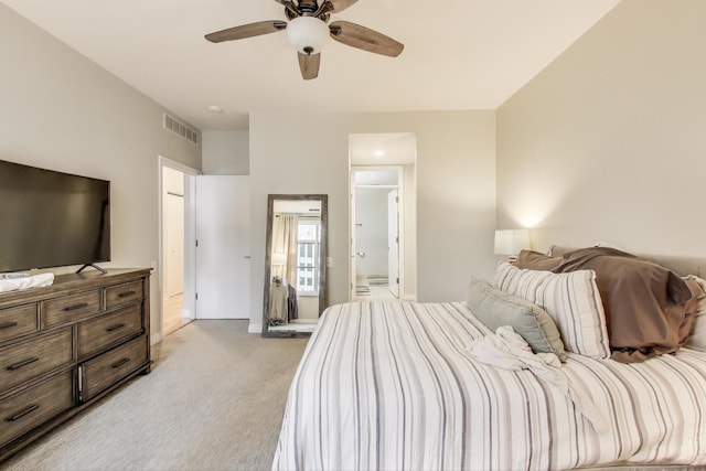 carpeted bedroom with ensuite bath and ceiling fan