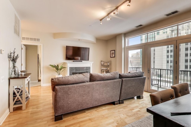 living room featuring a premium fireplace, rail lighting, and light hardwood / wood-style floors