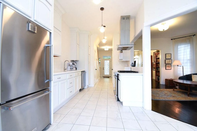 kitchen with hanging light fixtures, stainless steel appliances, white cabinets, island exhaust hood, and decorative backsplash