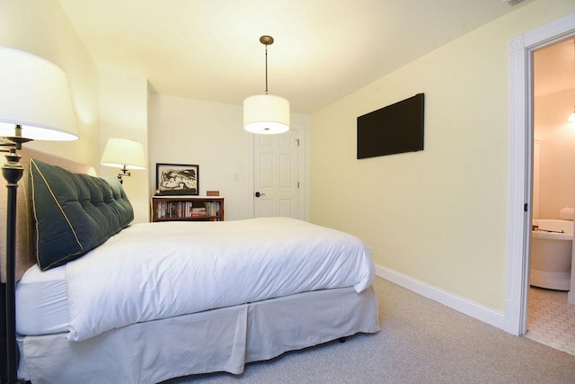 bedroom with ensuite bathroom and carpet flooring