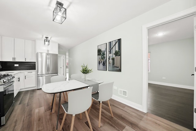 dining space with dark wood finished floors, visible vents, and baseboards