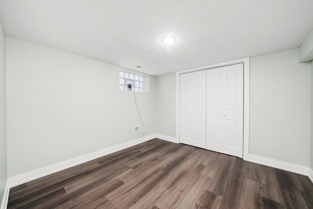 unfurnished bedroom featuring a closet, dark wood finished floors, and baseboards